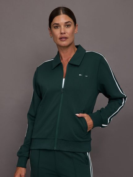 Woman wearing a green tracksuit with white stripes on a gray background