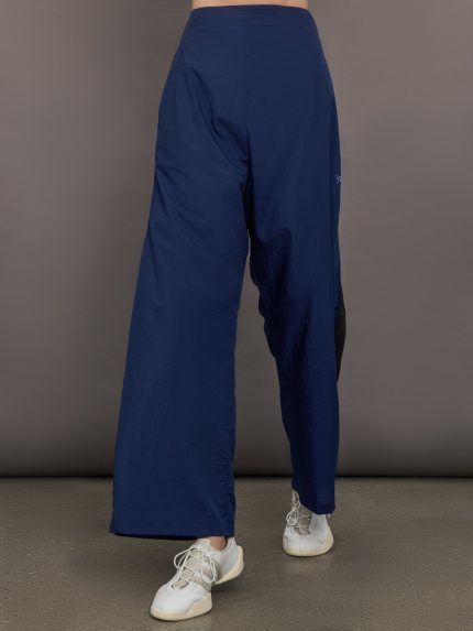 Model wears the Ulite nylon pants in dark blue with a high waist and relaxed fit.