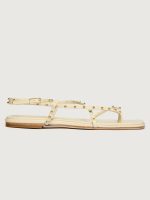 Creme colored flat sandal with round gold studs.