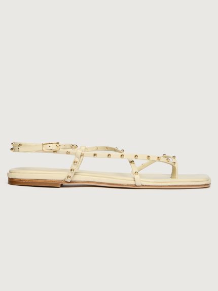 Creme colored flat sandal with round gold studs.